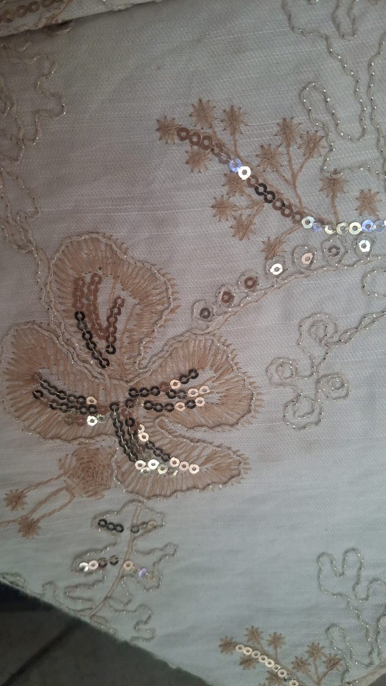 Primer plano de bordado floral claro con pequeños detalles brillantes