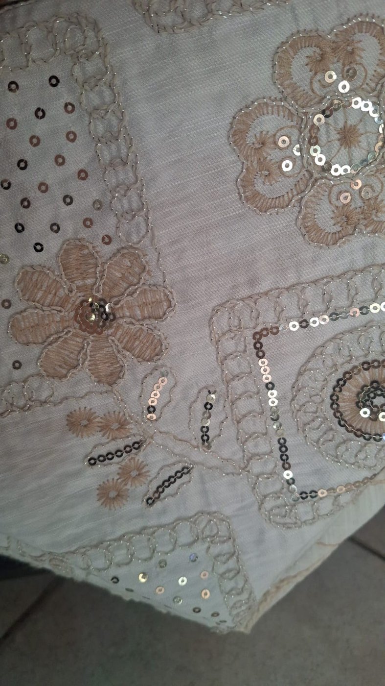 Detalle de flores bordadas y destellos sobre tela clara