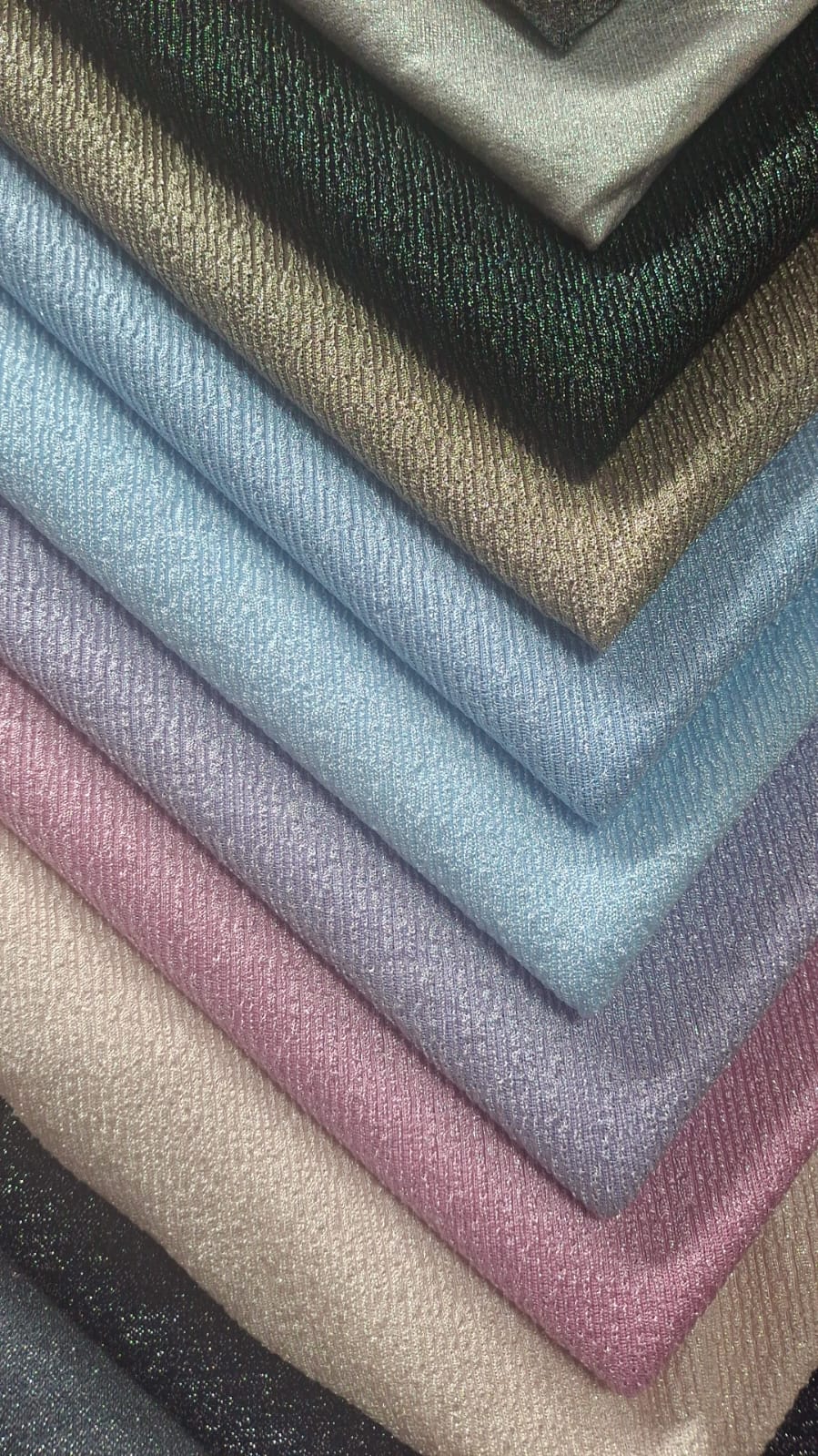 Telas brillantes apiladas en tonos azul, rosa, lila y dorado