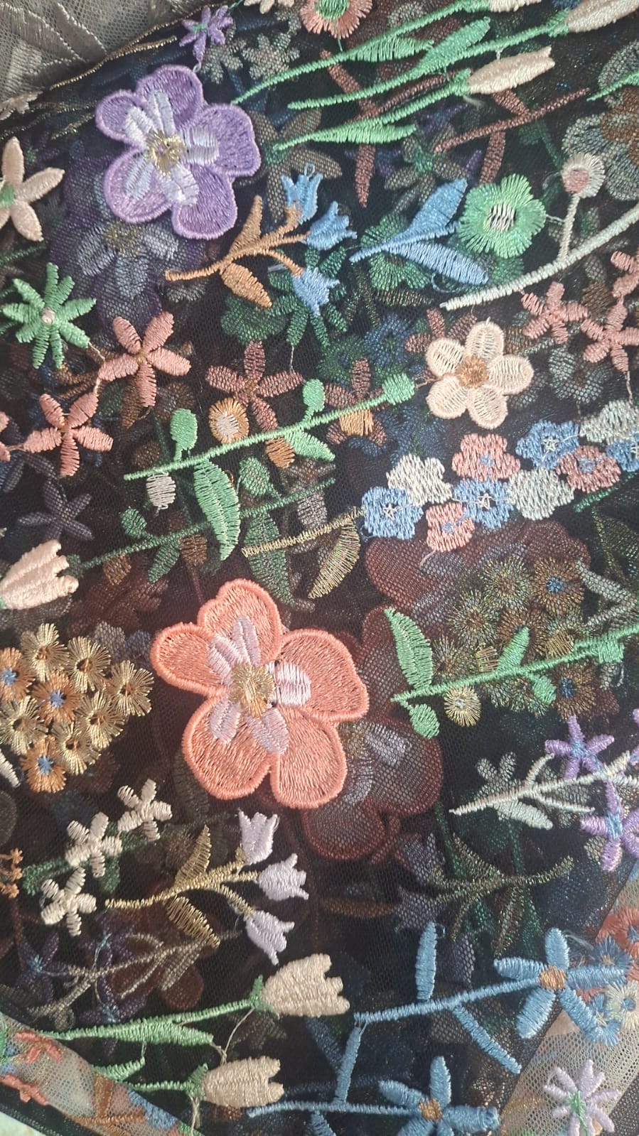 Flores bordadas multicolor en coral, lavanda, verde y azul sobre fondo oscuro