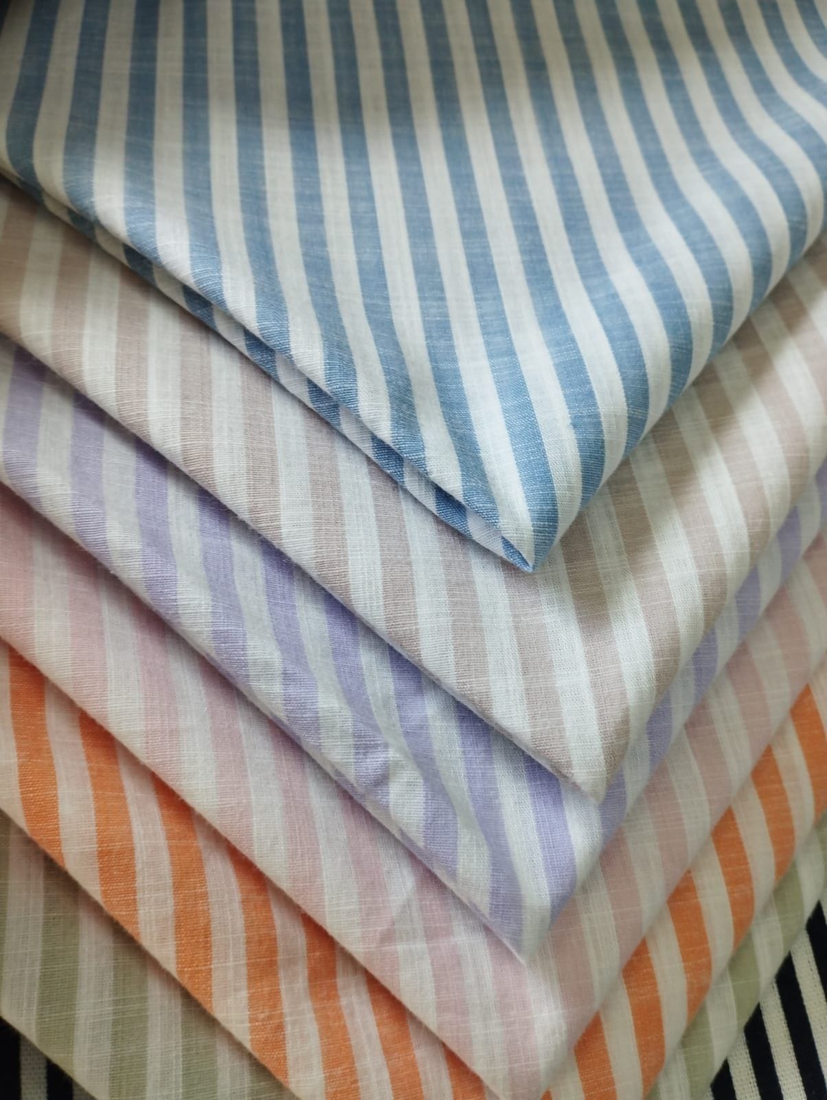 Telas finas con rayas en azul, lila, naranja y café sobre fondo claro
