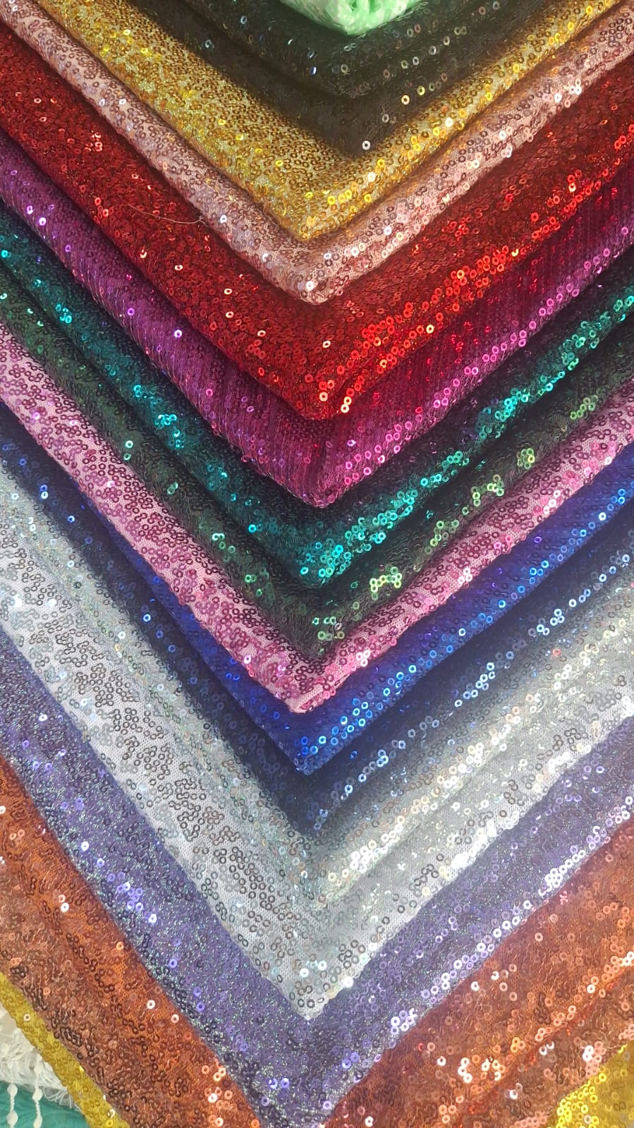 Capas de telas de lentejuelas en tonos dorado, rojo, rosa, verde, azul y plateado